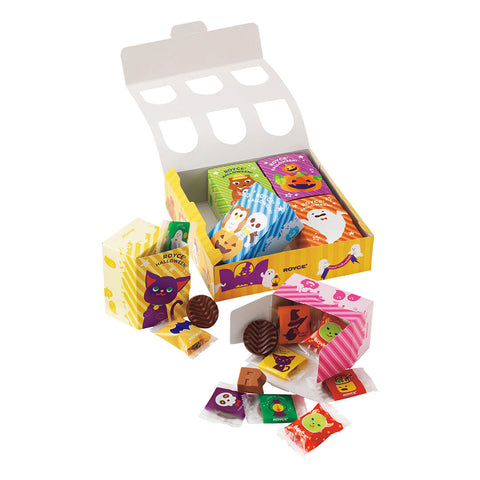 Image shows an open yellow printed box together with small boxes in the colors of green, violet, blue, orange, yellow, and pink. Seen in the picture are illustrations of ghosts, ghouls, animals, and other Halloween characters. Texts seen in the picture say ROYCE' Halloween. ROYCE'. Accents include loose wrapped chocolates in yellow, red, orange, and violet together with brown chocolate discs and an R-shaped chocolate. Background is in white.