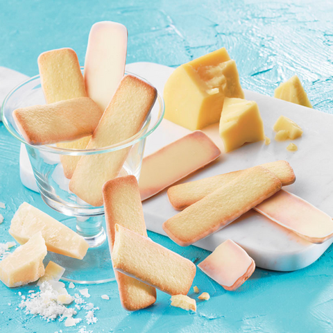 Image shows cookies coated with white chocolate on a chopping board and glass.