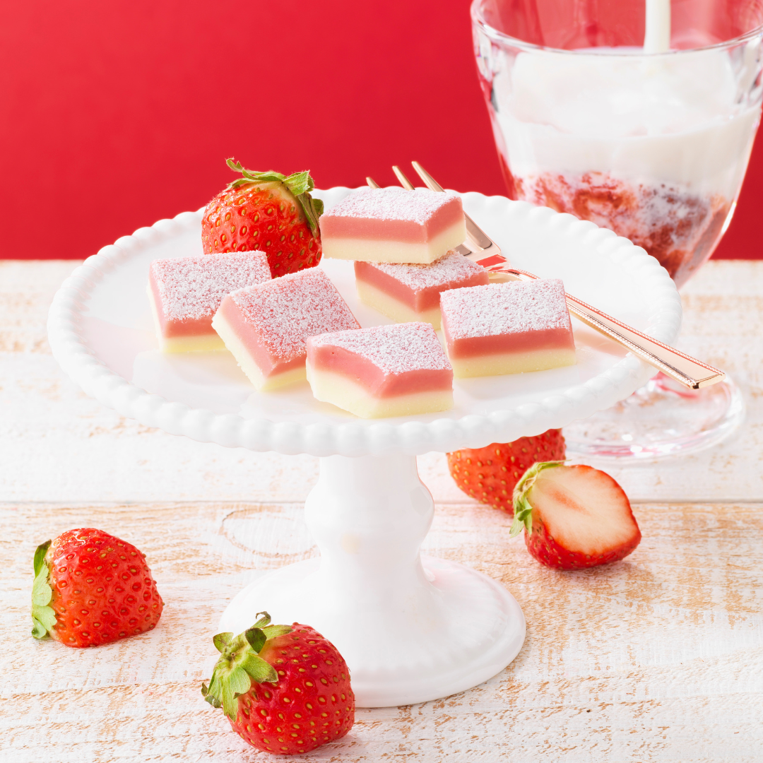 Image shows pink and white chocolate blocks on a plate with strawberries.